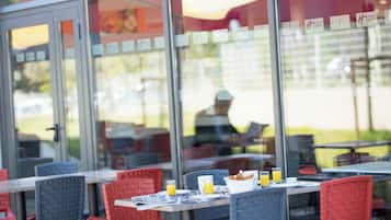 An outdoor seating area with tables and chairs, some with breakfast items.