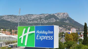 Une grande affiche publicitaire pour Holiday Inn Express, avec une chaîne de montagnes en arrière-plan.