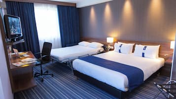 Una habitación de hotel con dos camas, un escritorio con una computadora portátil, una silla y un televisor.