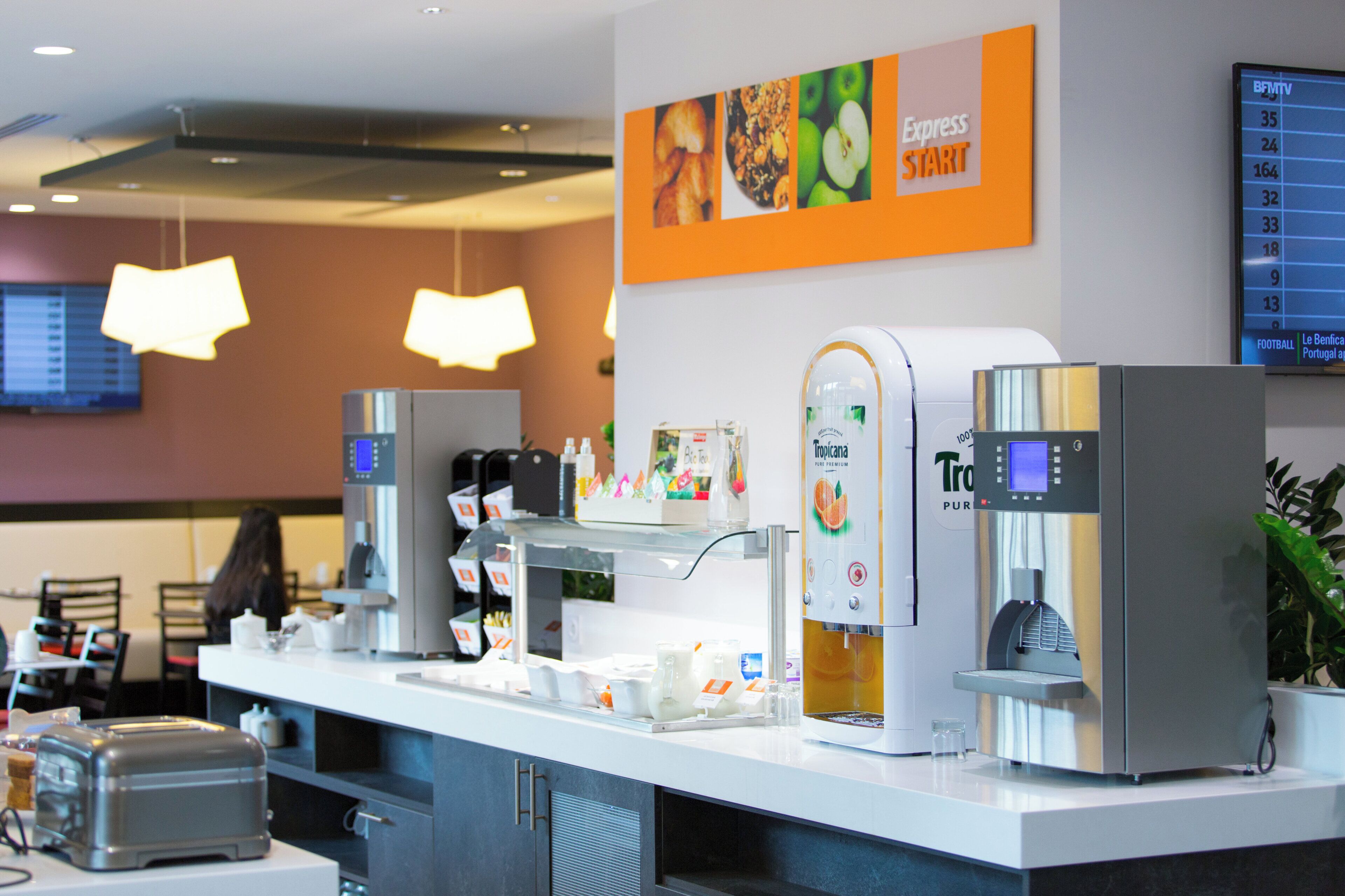 Een koffiehoek met een koffieapparaat, een waterdispenser en een menubord.