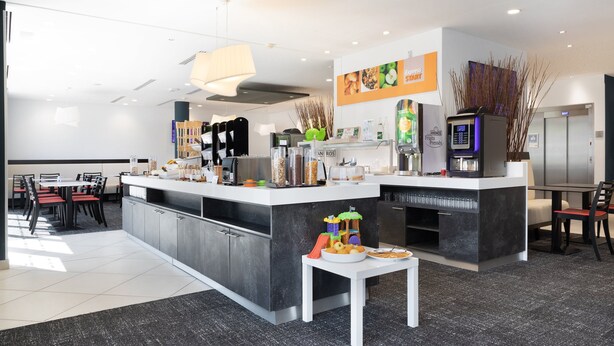 A modern kitchen with a central island, a dining area with red chairs, and a coffee machine. - Holiday Inn Express Toulon - Est by IHG (Toulon)