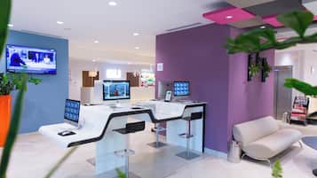 A modern reception area with a desk, two monitors, a television, and a seating area.