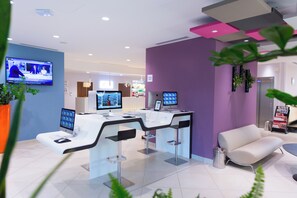 A modern reception area with a desk, two monitors, a television, and a seating area. - Holiday Inn Express Toulon - Est by IHG (Toulon)