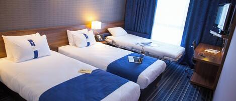 Una habitación de hotel con dos camas, un escritorio con ordenador y televisión.