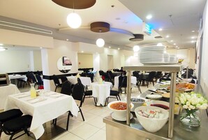Un comedor con varias mesas, sillas y un bufé con diversos alimentos.
