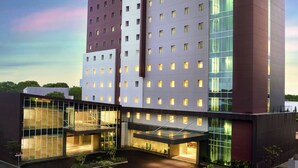 A modern hotel with a prominent "ibis HOTEL" sign, multiple floors, and a well-lit entrance. - ibis Makassar City Center (Makassar)
