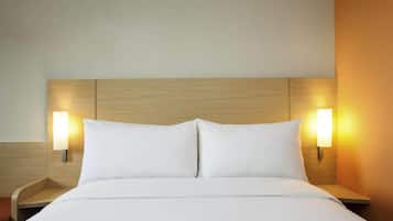 A hotel room with a wooden headboard, two bedside lamps, and a neatly made bed.