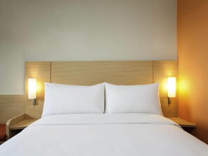 A hotel room with a wooden headboard, two bedside lamps, and a neatly made bed. - ibis Makassar City Center (Makassar)