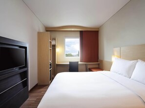 A hotel room with a bed, a TV, a desk, and a window. - ibis Makassar City Center (Makassar)