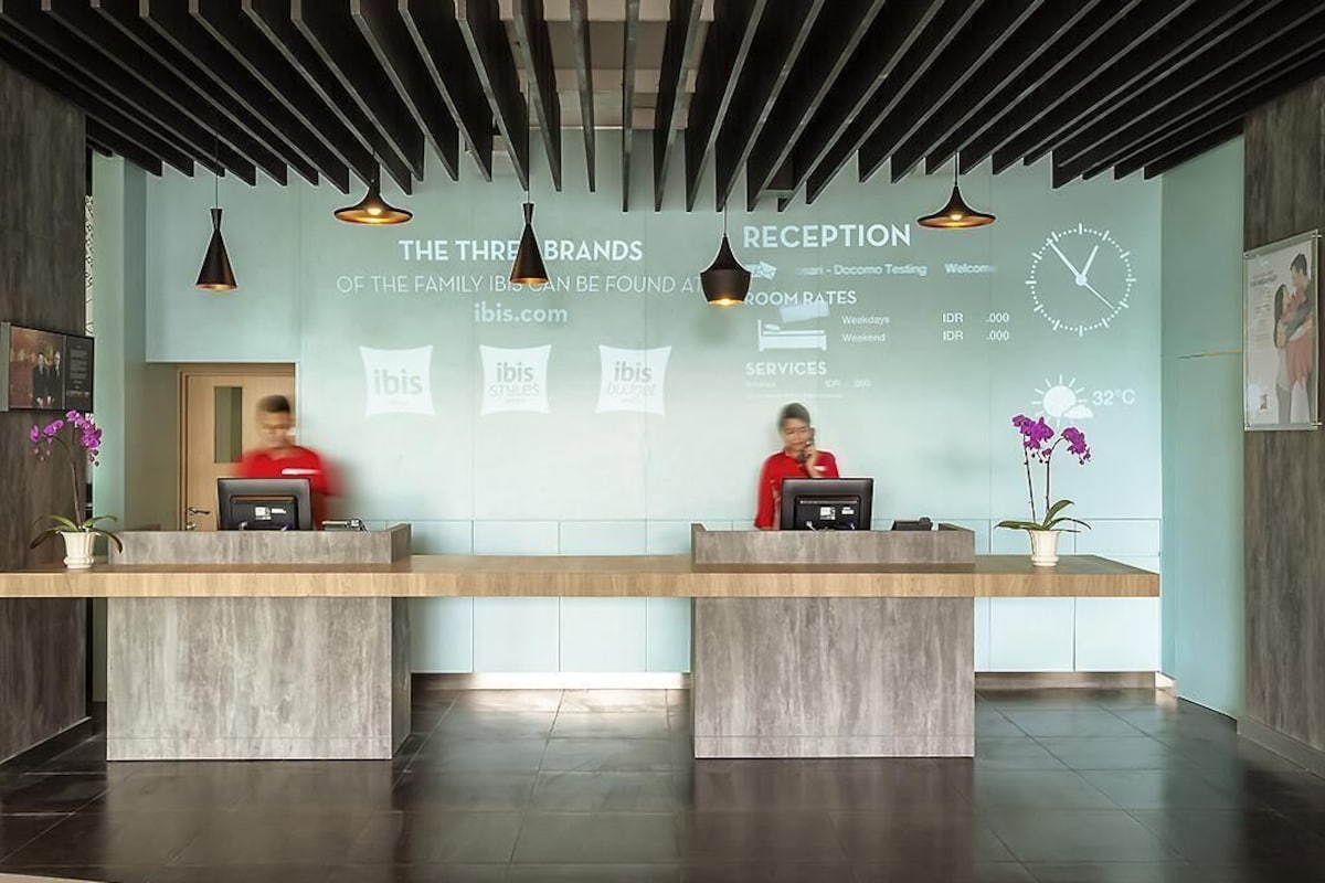 A reception desk with two staff members, a clock, and a temperature display.
