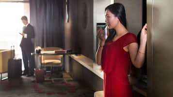 A hotel room with a bed, a desk, a chair, and a suitcase.