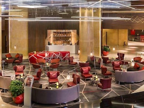 A modern lobby with a bar area, seating arrangements, and a reception desk.