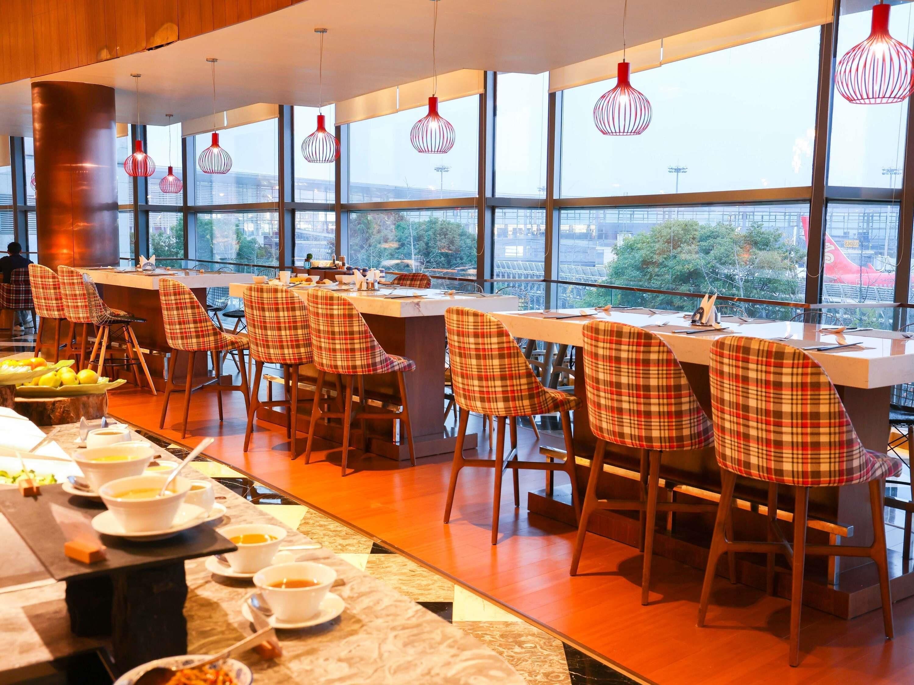 Ein Restaurant mit einer langen Theke, karierten Stühlen und Blick durch große Fenster.