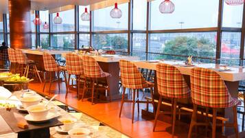 Ein Restaurant mit einer langen Theke, karierten Stühlen und Blick durch große Fenster.