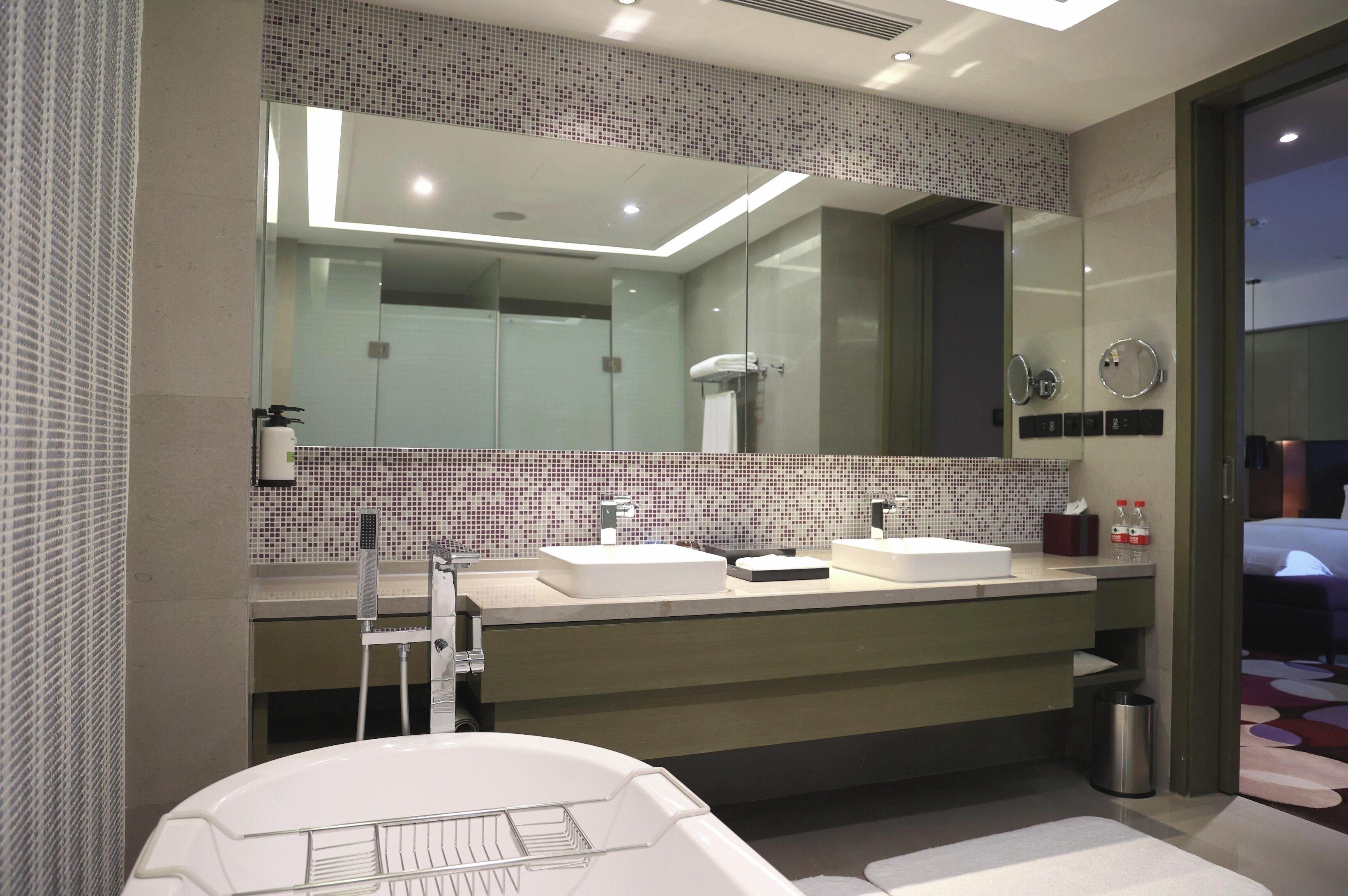 Une salle de bain moderne avec deux lavabos, un grand miroir et une baignoire.