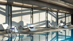 Una piscina con sillas de descanso y un parasol.