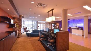 A modern office space with a reception desk, computer workstations, a seating area, and a stone accent wall.