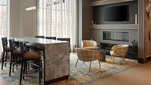 A modern living room with a marble coffee table, a flat-screen TV, and a fireplace. There are several chairs and a sofa.