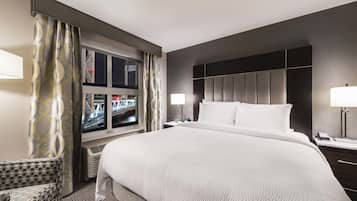 Quarto de hotel com uma cama grande, televisão, escrivaninha e uma cadeira.