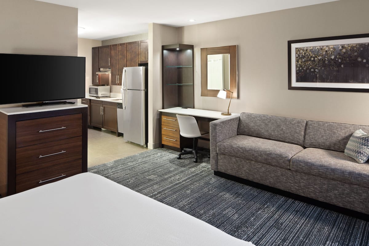 Une chambre d’hôtel équipée d’un lit, d’une télévision, d’une kitchenette, d’un bureau, d’une chaise et d’un canapé.