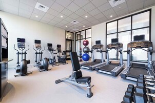 Un gimnasio con cintas de correr, elípticas y pesas libres.