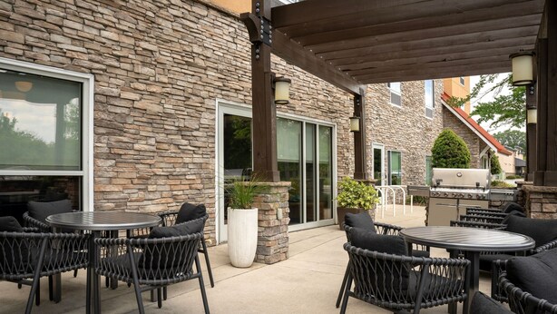 Une terrasse extérieure avec des meubles en osier, des murs en pierre et un barbecue.