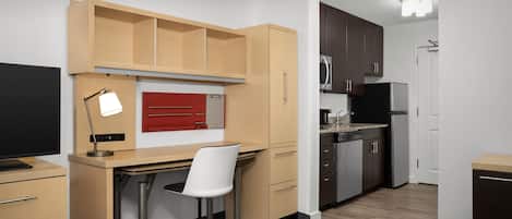 Una cocina compacta con encimera de madera, microondas integrado y refrigerador.