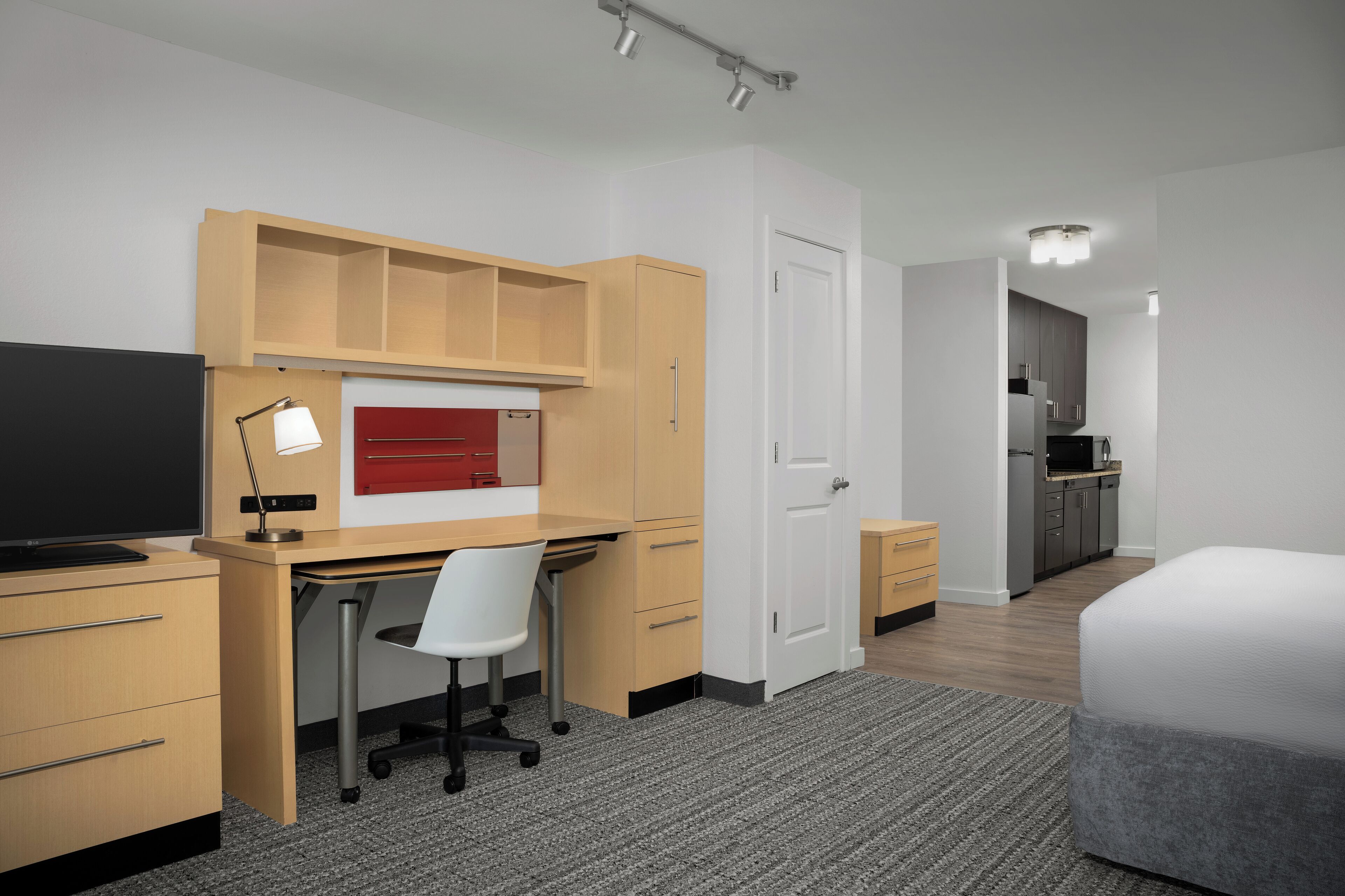 A compact hotel room with a desk, chair, and bed.