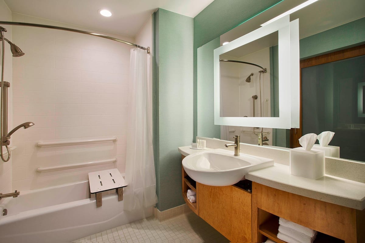 A modern bathroom with a bathtub, a large mirror, and a vanity with a sink.