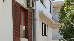 A narrow alleyway with a wooden chair, a potted plant, and a flag. - Atlantis Hotel (Agios Nikolaos)