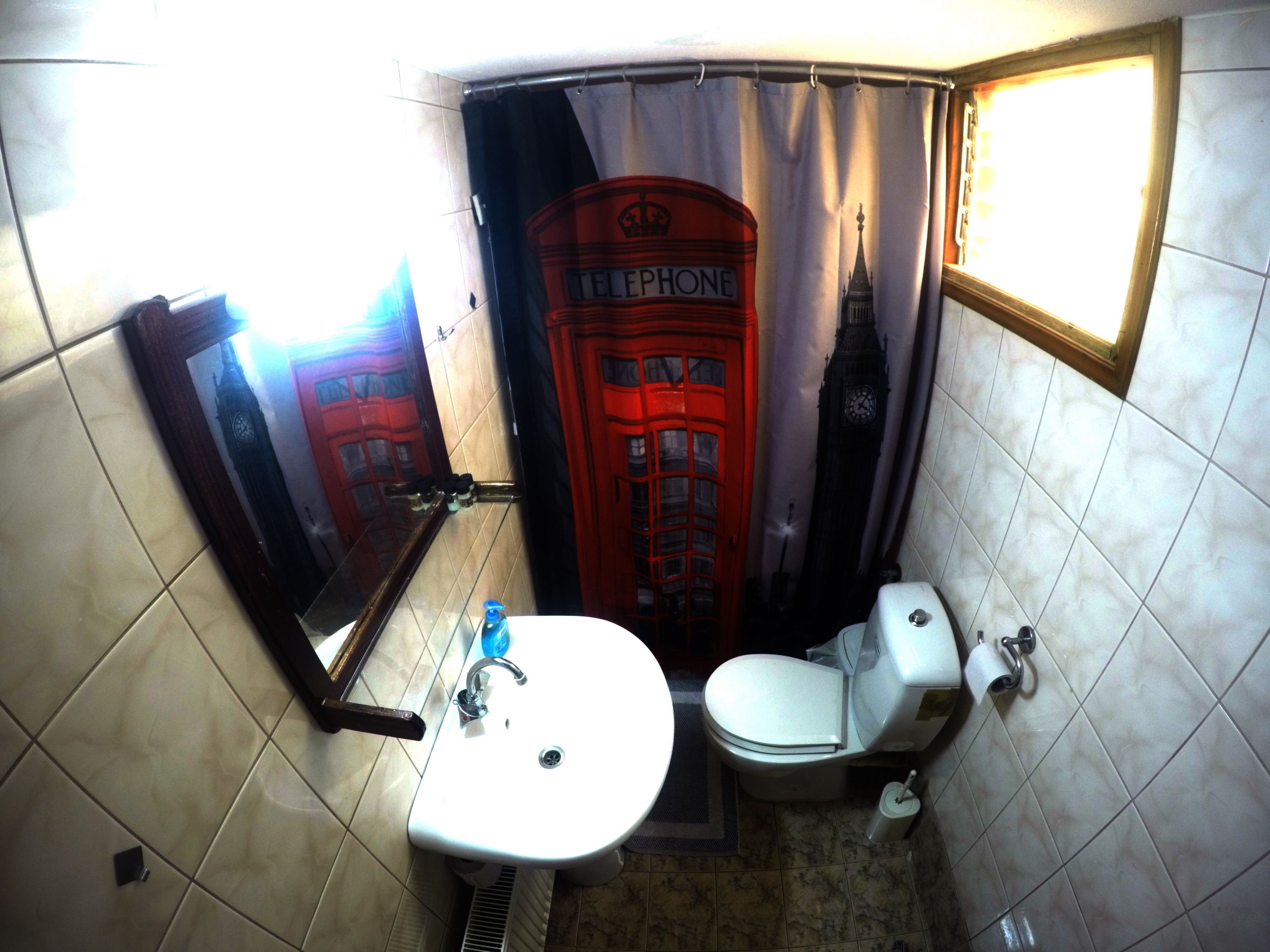 Une salle de bain avec un lavabo, des toilettes et un motif représentant une cabine téléphonique rouge sur le mur.