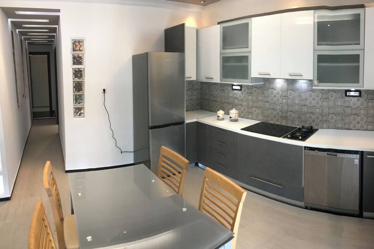 A compact kitchen with a dining area, featuring a refrigerator, stove, sink, and cabinets.