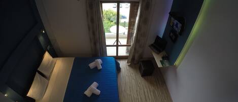 Quarto de hotel com cama, escrivaninha e janela com cortinas.
