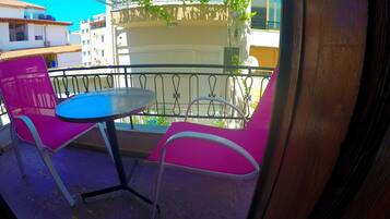 Un balcón con una mesa redonda y dos sillas rosas.