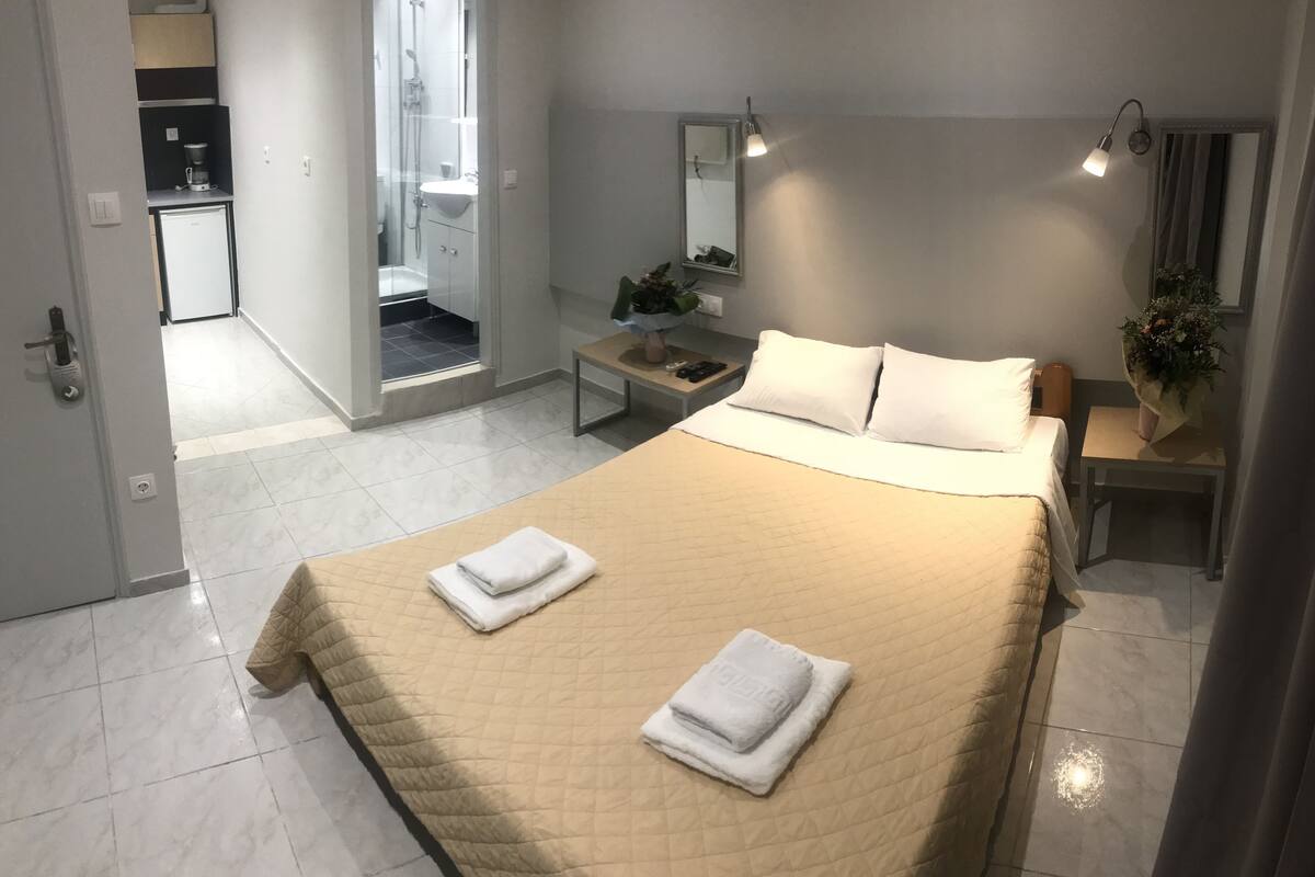 A hotel room with a bed, bedside table, and a bathroom visible through an open door.