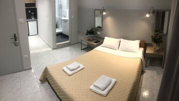 Quarto de hotel com cama, mesa de cabeceira e banheiro visível através de uma porta aberta.