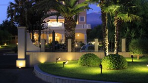 Una entrada de hotel con un camino empedrado, palmeras y senderos bien iluminados.