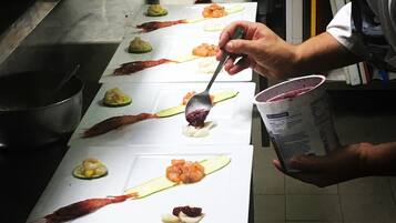 Un chef preparando platos sobre una mesa blanca larga en una cocina.