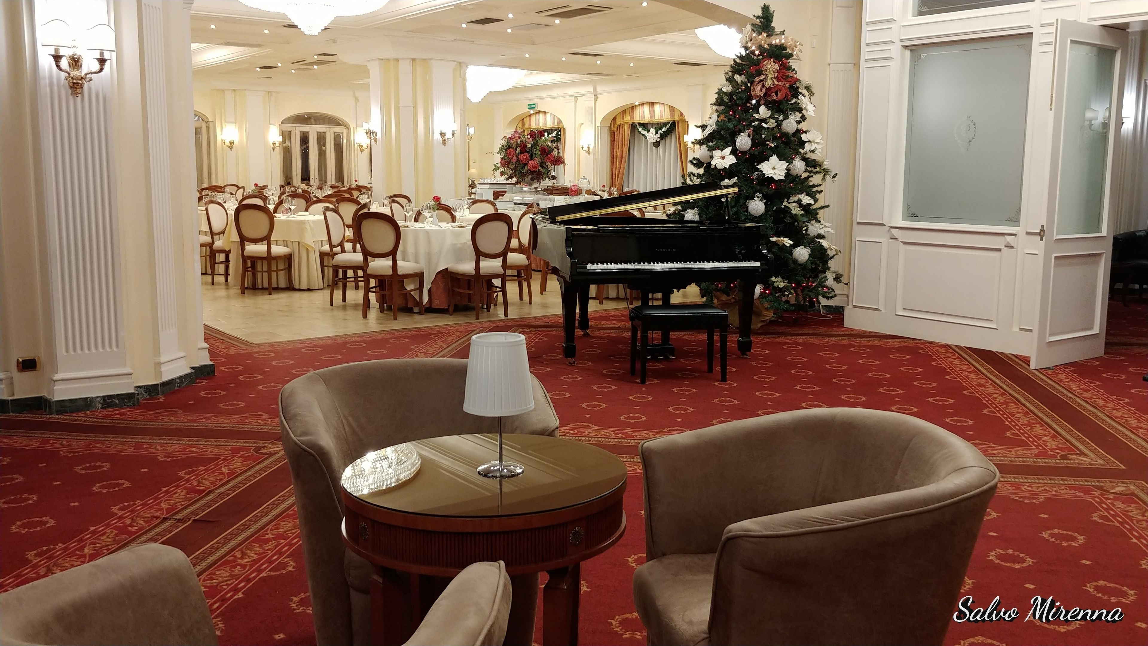Un salón imponente con un piano de cola, un árbol de Navidad y una elegante disposición para el comedor.