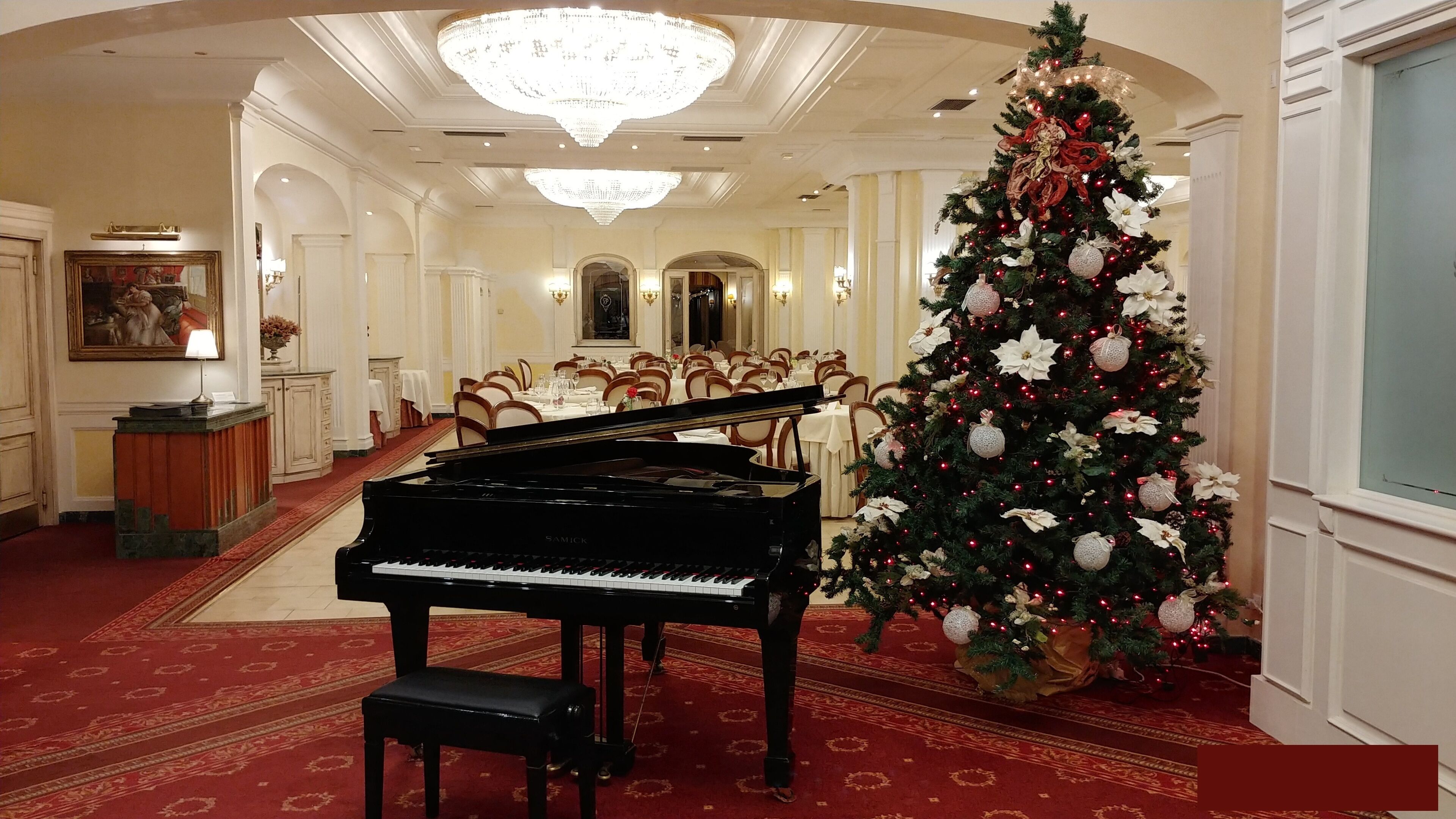 Un salón imponente con un piano de cola, un gran árbol de Navidad y una elegante disposición para el comedor.