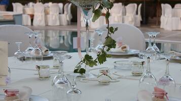 A table set for a formal event with clear glassware, plates, and a centerpiece with greenery.