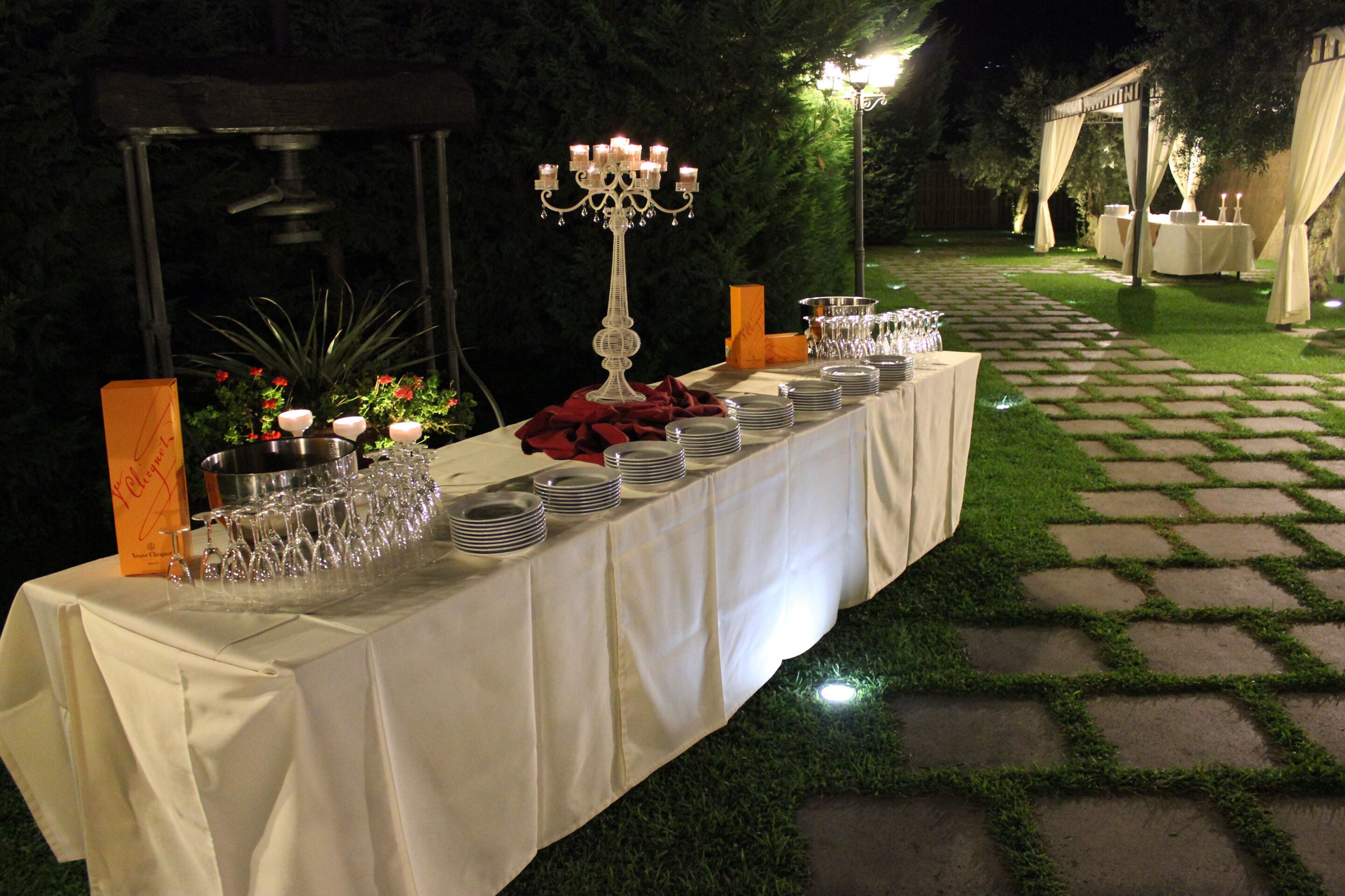 Un montaje para comedor al aire libre con una mesa larga, velas y un candelabro decorativo.