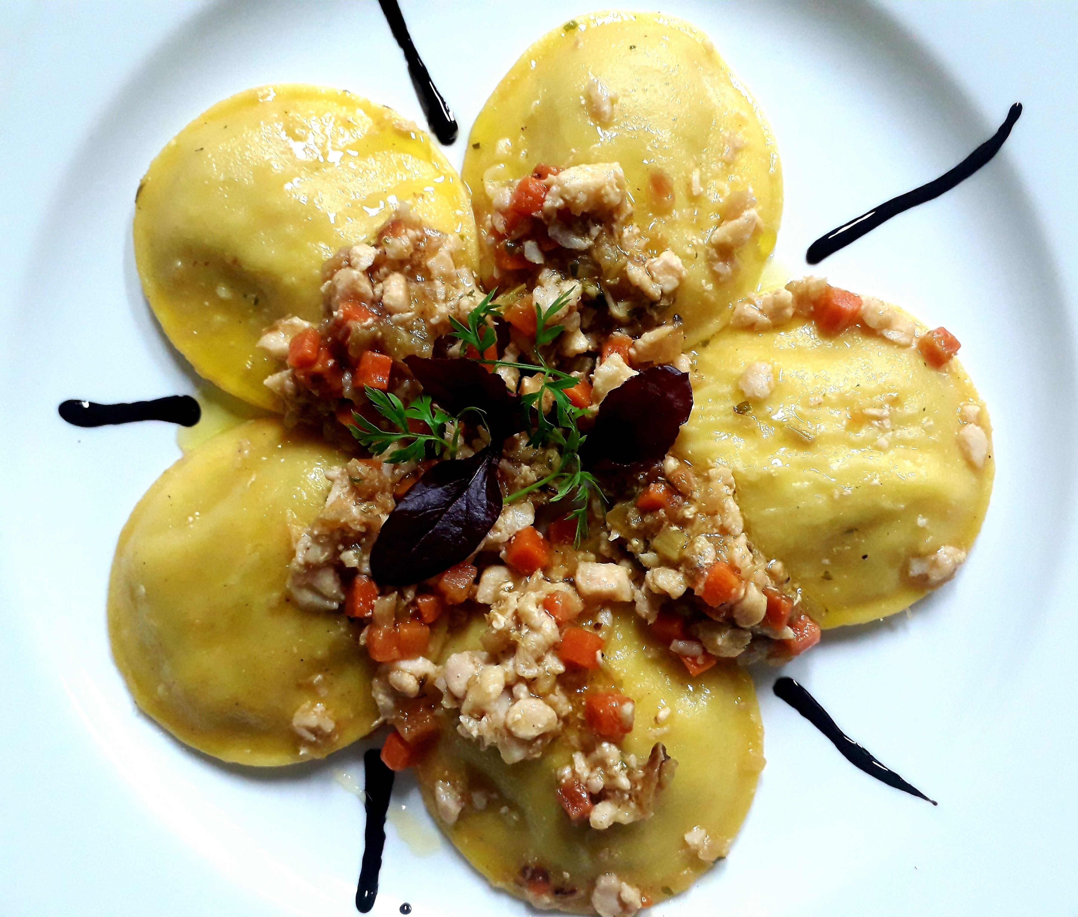 Ein Teller Essen, garniert mit Kräutern und einem dekorativen schwarzen Klecks.