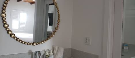 A bathroom with a round mirror, a sink, and a towel holder.