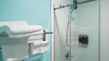 A glass-enclosed shower with a handheld showerhead and a wall-mounted control panel.
