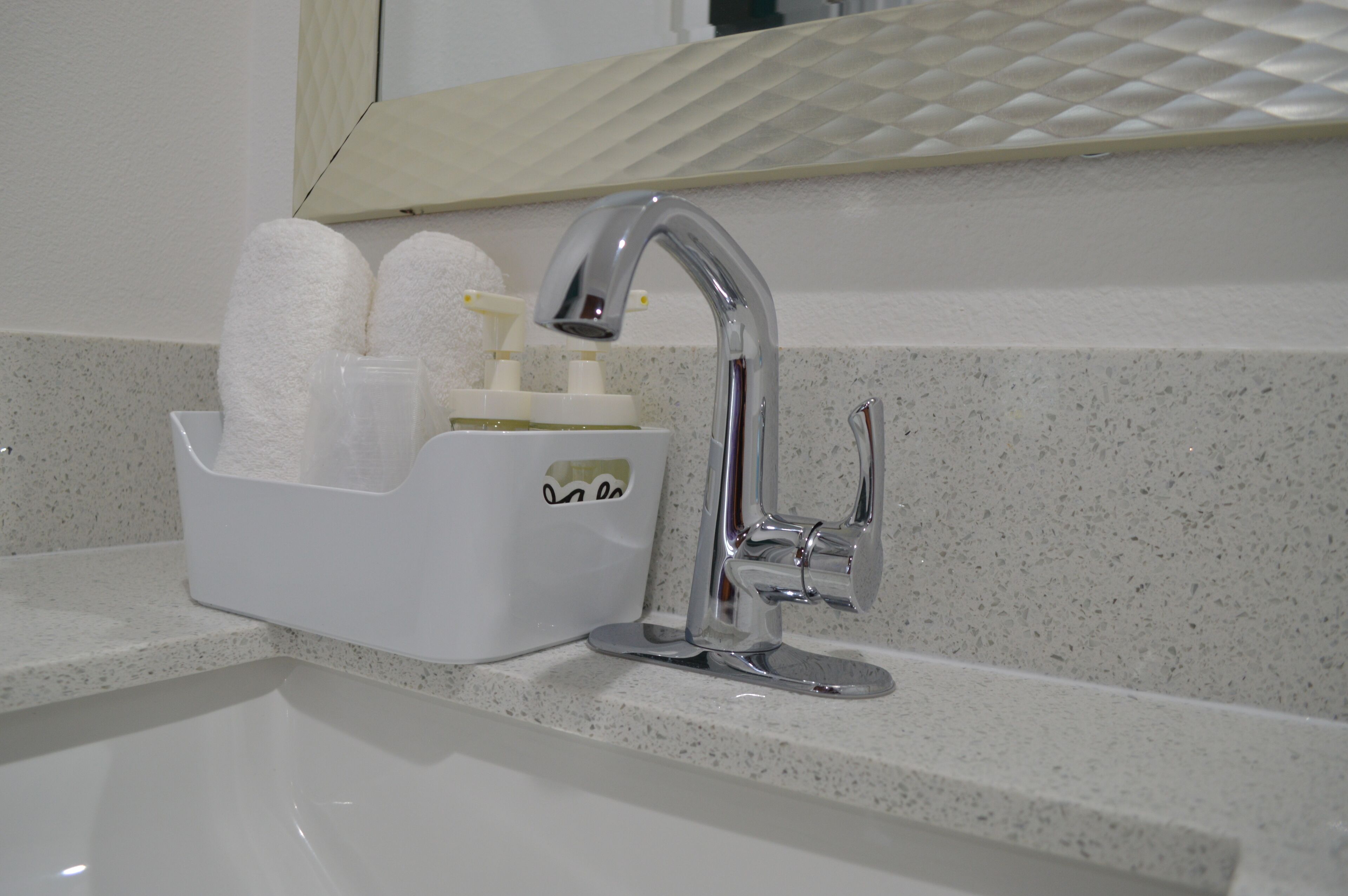 A bathroom sink with a chrome faucet, a soap dispenser, and a towel holder with two white towels.