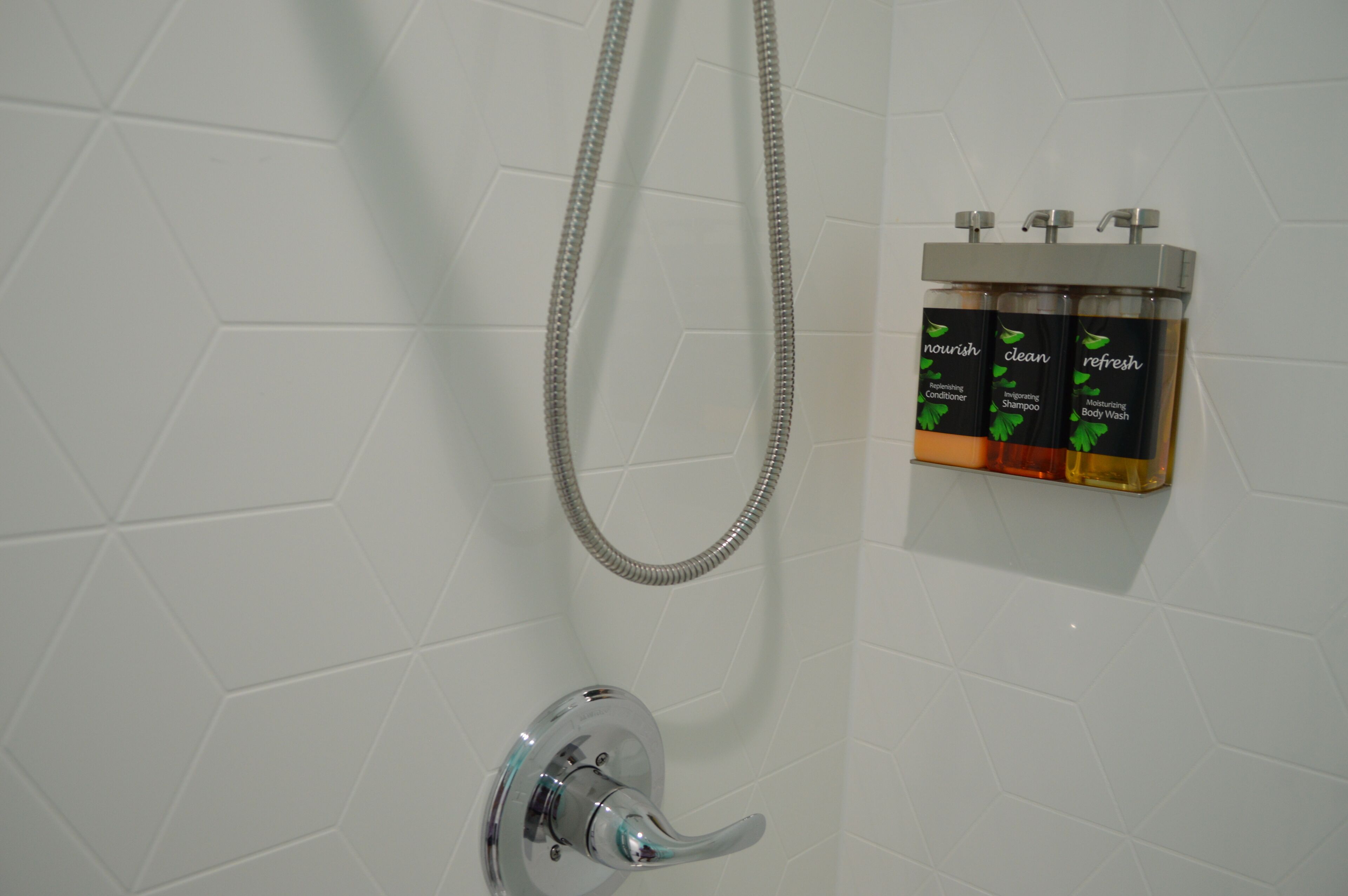 Eine Dusche mit Duschbrause und Shampoo-Spender an der Wand.