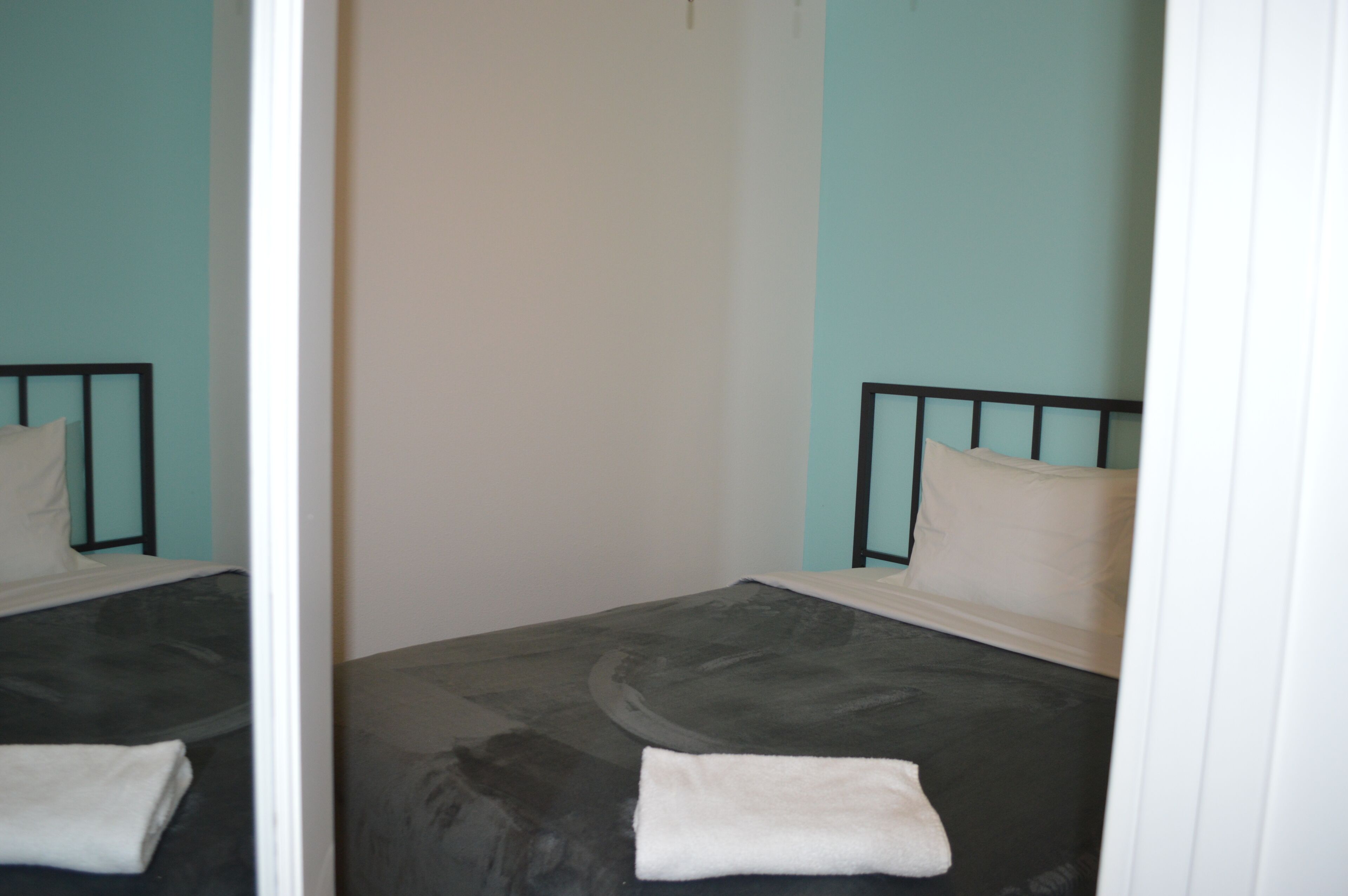 A room with a bed, a mirror, and a plain wall.
