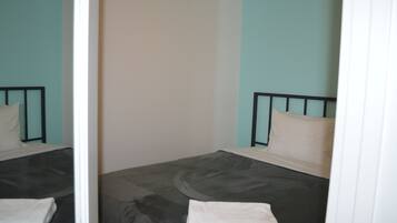 A room with a bed, a mirror, and a plain wall.