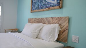 Un lit bien fait, avec du linge de lit blanc, une tête de lit en bois et une petite table de chevet en bois à côté.